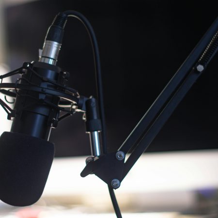 Close-up of a condenser microphone in a studio setting, ideal for podcasts and audio recording.